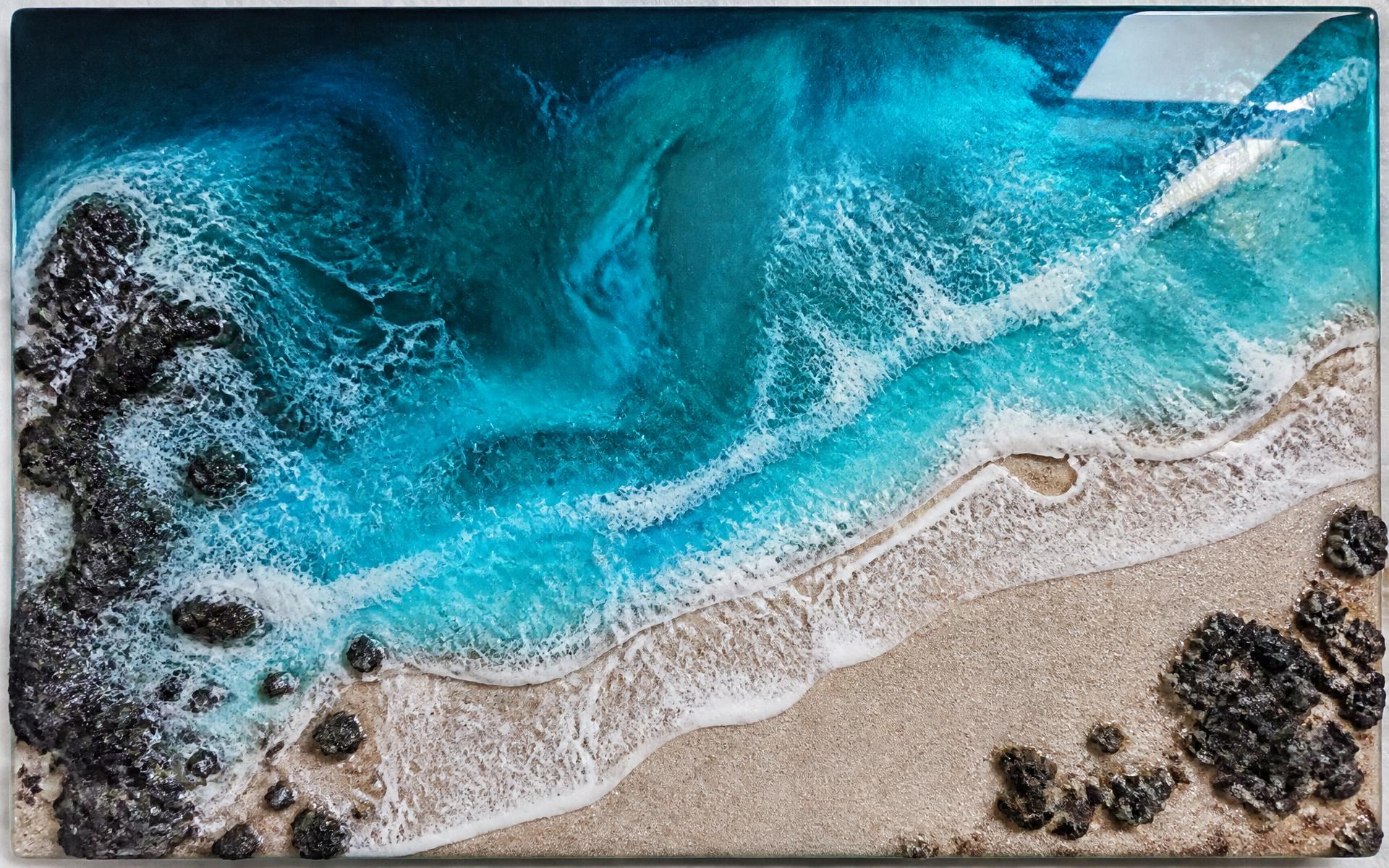 Obra de resina epoxi con olas turquesa, arena y roca volcánica
